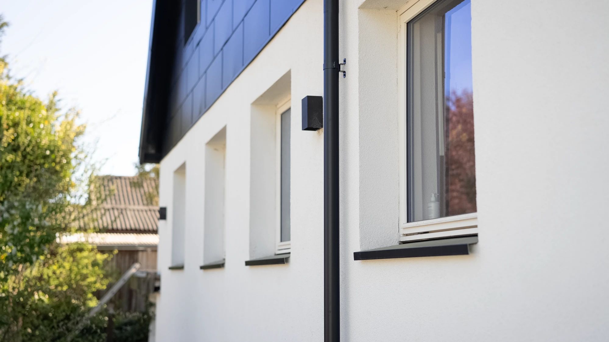 Hvidt hus med sort tag set fra haven efter facadearbejde